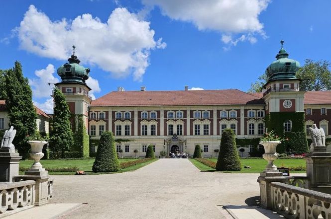 Zamek - elewacja zachodnia, słoneczny dzień, białe obłoki, lato. Ujęcie z mostu zachodniego prowadzącego do głównych drzwi rezydencji