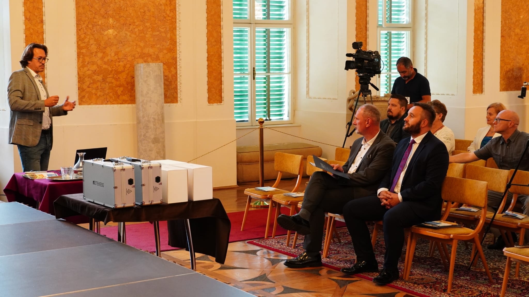 Sala Balowa, prezes RARR Mariusz Bednarz mówi do zebranych, stoi. Przed nim siedzący słuchacze.  Na stole pudełka z goglami VR