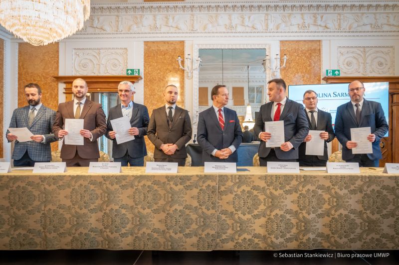 Sala Balowa, 8 mężczyzn stojących za stołem - po podpisaniu porozumienia Dolina Sarmacka