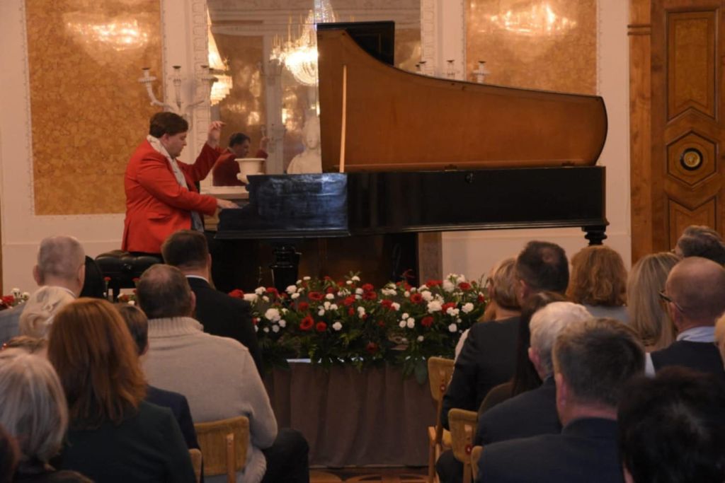 Koncert fortepianowy w Sali Balowej. Prof. H. Rutkowski gra na fortepianie Leszetyckiego. Publiczność siedzi na kszesłach