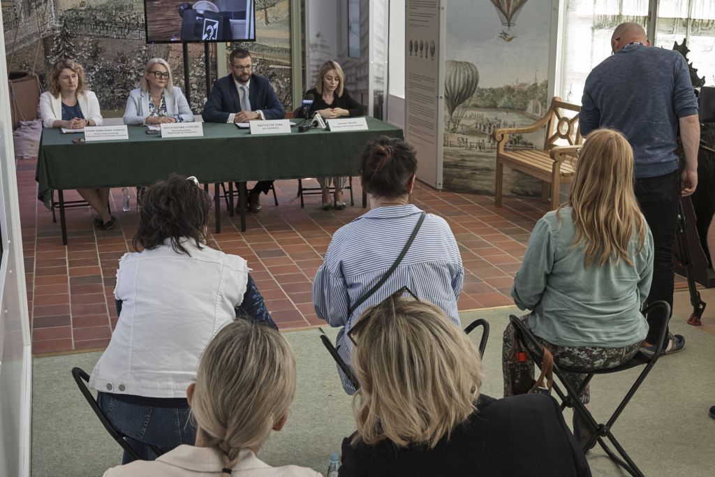 Prelegenci konferencji siedzący przy stole, na pierwszym planie zbliżenie na dziennikarzy. Miejsce wydarzenia: d. Oranżeria - ekspozycja na 1 piętrze