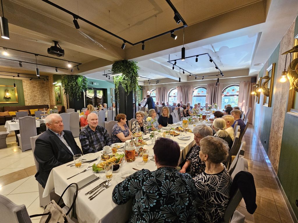 Sala restauracyjna, widok na stoły przy których siedzą zaproszeni goście. 