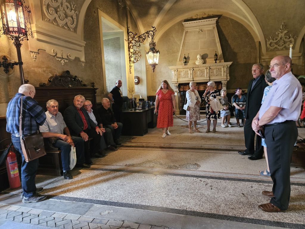 spotkanie  emerytowanych pracowników MZŁ - sień zamkowa, uczestnicy spotkania w półokręgu - siedzą i stoją, słuchają osoby prowadzącej spotkanie - wstęp do zwiedzania ekspozycji zamku